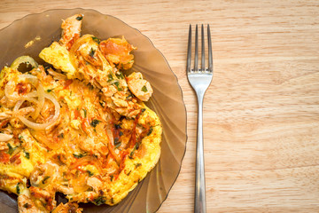 omelette with onion, tomatoes, chicken and parsley on a dish on a wooden background with copy space for your text