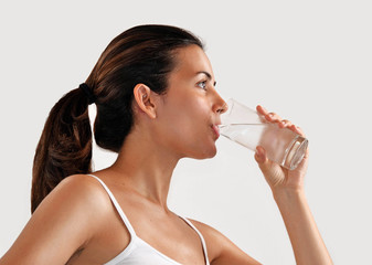 Joven mujer latina bebiendo un vaso de agua
