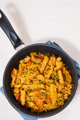 meat with rice and vegetables in a frying pan