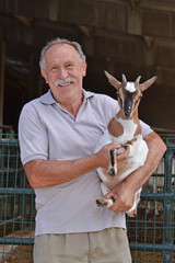 Retrato de un granjero veterinario sujetando una pequeña cabra.