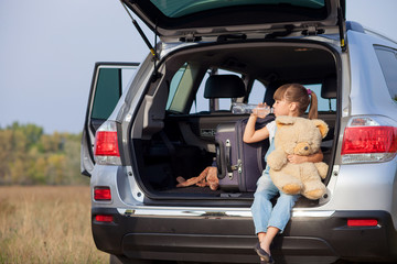 Cute small female child near transport in meadow