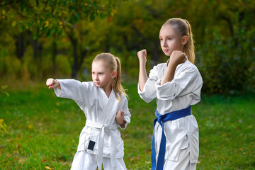 girls in white kimono during training karate exercises at summer
