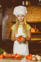Funny smiling chef girl holding tomatoes at restaurant kitchen