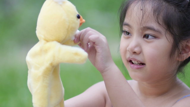 Little Asian girl playing with hand puppet in the garden