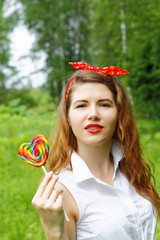 girl with a lollipop in the trees in the summer