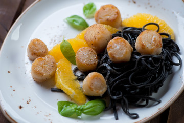 Roasted sea scallops with tagliatelle and orange fillet, closeup