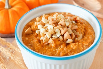 Bowl of autumn pumpkin oatmeal close up with walnuts, chocolate and peanut butter chips