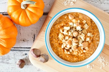 Bowl of autumn pumpkin oatmeal with walnuts, chocolate and peanut butter chips, overhead table scene
