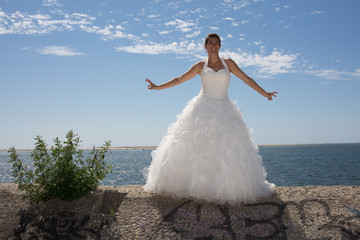 A married woman bride in her wedding dress in sunshine on a beautiful tropical beach