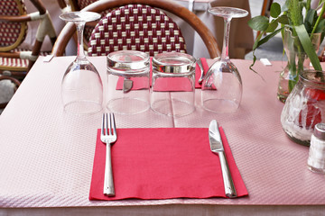 Table with napkins, knife, fork, glasses wot wine and water in cafe