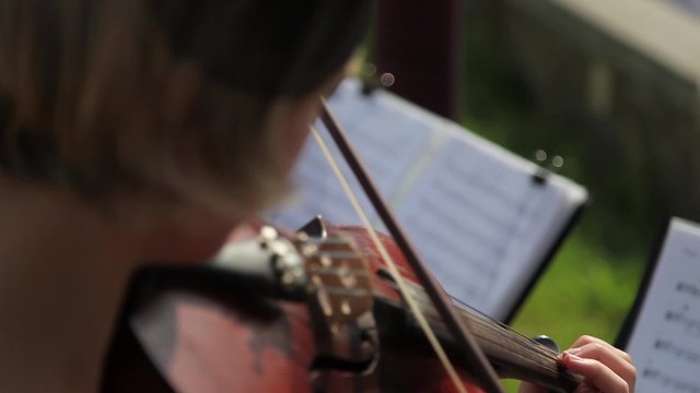A female musician playing a violin in an orchestra. Close up detail shot.