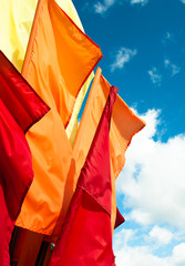Yellow, orange and red blank flags against the blue sky