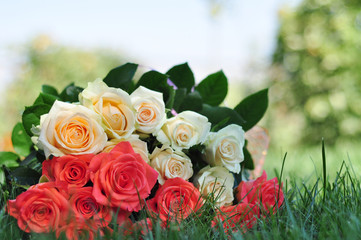 Wonderful festive bouquet of roses lying on the grass on a blurr