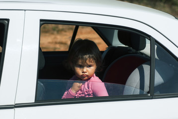 little girl sitting alone in the car and sad