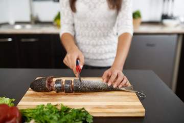 girl cut fish to cook tasty dish
