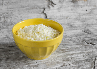 cottage cheese in yellow ceramic bowl on bright wooden surface