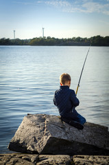 Small boy fishing from sea coast