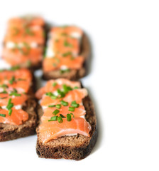 Sandwiches with salted salmon, rye bread, cream cheese and finely chopped green onions on a white background. Selective Focus, Focus on the front of the sandwiches.