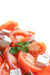 Fresh vegetable salad with tomatoes, feta cheese, red onion and mint leaf on white background.