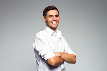 Portrait of young happy smiling business man, isolated over gray background