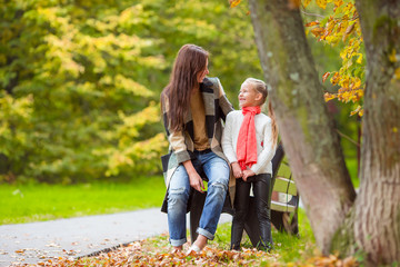 Adorable little girl with mother in autumn park outdoors