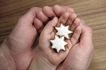 große Hände halten kleine Kinderhände mit Zimtsternen
