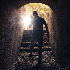 Young man with radio goes out of dark stone tunnel