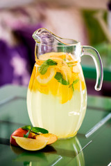 Preparation of the lemonade drink. Lemonade in the jug and lemons with mint on the table