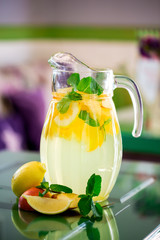 Preparation of the lemonade drink. Lemonade in the jug and lemons with mint on the table
