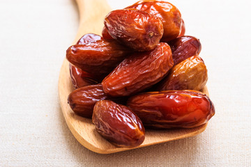 dried dates on wooden spoon cloth background