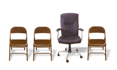 Executive's Chair - One cushioned office chair between several  plain folding chairs