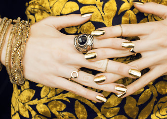 woman hands with golden manicure lot of jewelry on fancy dress