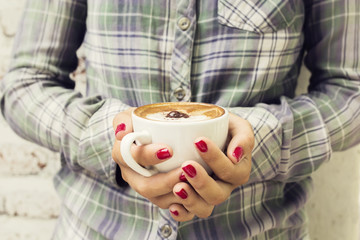 Hipster girl holding a cup of cappuccino