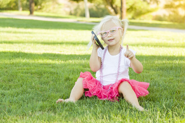 Fototapeta premium Little Girl In Grass Talking on Cell Phone