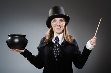 Harry Potter girl with magic stick and pot against gray