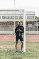 Athlete leaned on the goalpost, listening to music