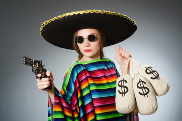 Girl in mexican poncho holding handgun and money sacks against g