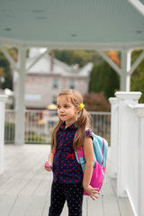 little girl with pony tails and backpack going to school