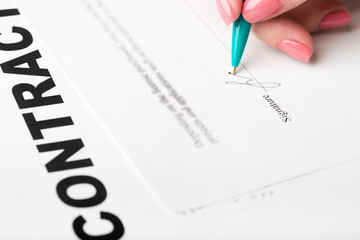 female hand signing a contract.