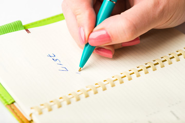 Close-up of a female hand writing on an blank notebook with a pe