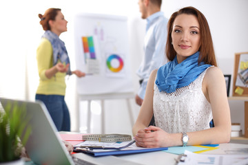 Portrait of attractive female  designer sitting on desk  in