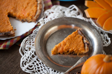 Homemade pumpkin pie with chocolate dough serving on German silver plate