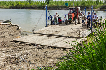 People are moving manual ferry boat across the river.