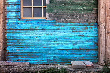 Blau gestrichene Wand an einem verwittertem Holzhäuschen