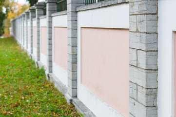 Fototapeta na wymiar Pink and white concrete fence with stone columns
