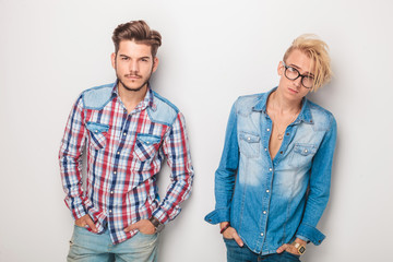 two young men standing with hands in pockets