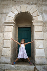 Fototapeta na wymiar Little girl on old doors in Stari Grad, Hvar