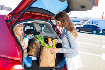 Woman and her daughter after shopping in a mall or shopping centre and driving home now with her...