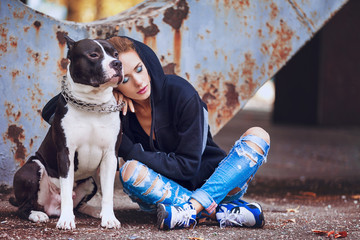 modern punk fashion, portrait of a beautiful model posing with American staff terrier over street...