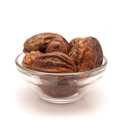 Front view of Organic Inknut or Harr (Terminalia chebula) in glass bowl isolated on white background.